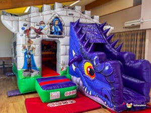 A colorful inflatable castle with a dragon slide, featuring vibrant cartoon characters and playful designs, suitable for kids' entertainment.