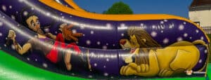A colorful inflatable slide features a cartoonish lion lounging beside a cheerful performer holding a microphone, set against a starry background.