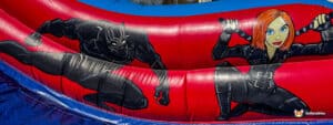 A colorful inflatable slide featuring dynamic images of Black Panther and Black Widow in action poses against a red and blue background.