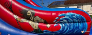 A vibrant inflatable slide featuring a heroic figure bursting through waves, showcasing vivid colors and dynamic action.