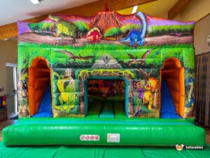 A colorful dinosaur-themed inflatable bounce house featuring vibrant graphics of dinosaurs and children, perfect for playful fun.