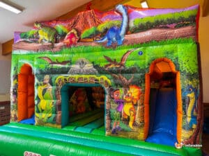 Colorful dinosaur-themed inflatable dinosaur double slide cabin featuring playful scenes of dinosaurs and explorers in a vibrant jungle setting.