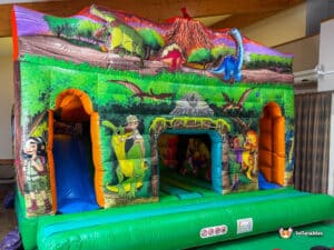 A vibrant dinosaur-themed inflatable bounce house featuring colorful illustrations of dinosaurs and children, set against a lush background.