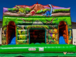 A colorful dinosaur-themed inflatable dinosaur double slide cabin featuring cartoon characters, a slide, and a vibrant jungle backdrop.