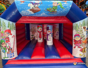 Full view of the inflatable bouncy castle, featuring the Christmas-themed art across the top and sides, with red and blue inflatable floor and pillars inside.