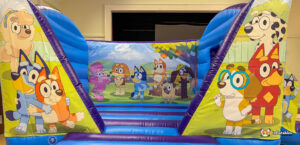 Close-up of the front of the Bluey inflatable, featuring the hugging Bluey and Bingo on the left column, a large group scene on the back wall, and Winton and Rusty on the right column.