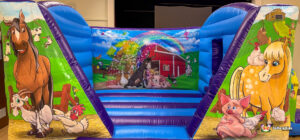 A focused view of the interior and front pillars, showing the contrast between the inflatable's structural blue walls and the vivid, busy farm animal murals.