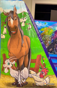 Close-up of the left-side column art featuring a brown horse, a white goat, and a red-crested rooster standing in a farmyard with sheep in the distance.