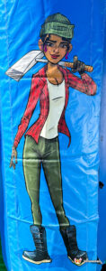 Artwork on a side pillar of the inflatable showing a stylized female lumberjack character in a red flannel shirt holding an axe.