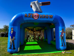 Frontal view of the inflatable Axe Throwing Arena set up outdoors on a lawn, featuring a large inflatable axe on top and cartoon lumberjack characters on the front pillars.