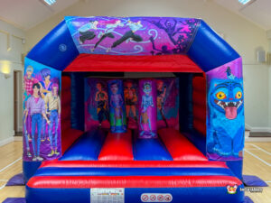 xFull frontal view of an inflatable bouncer featuring vibrant purple and pink artwork with anime-style characters and monsters.