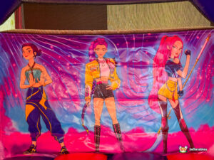 Artwork on the back wall featuring three anime-style female characters in stylish outfits.