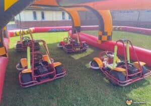 Exciting go-karting event in a park, displaying karts racing on a track amidst trees and cheering spectators.